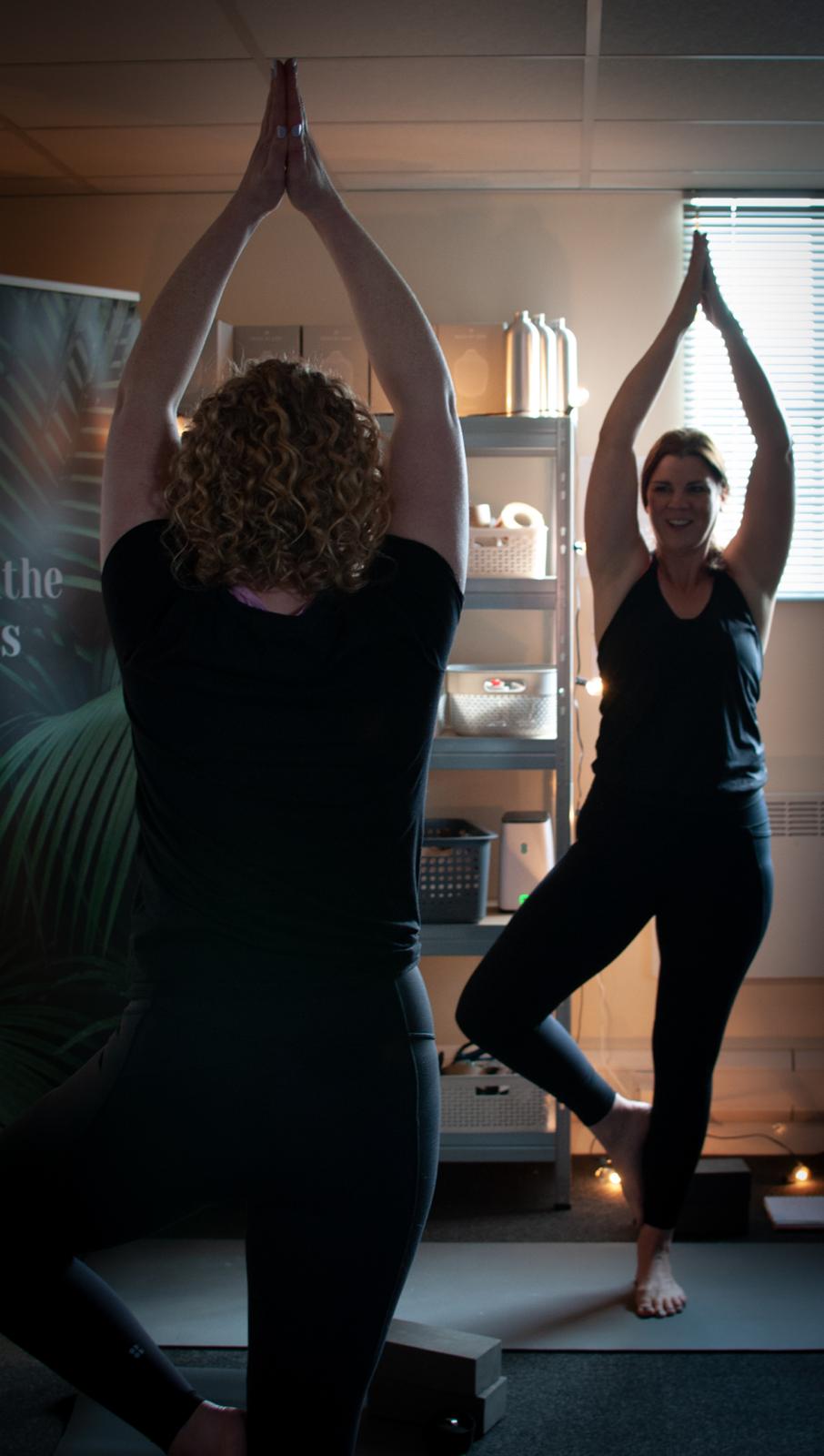 A yoga teacher guiding a student through tree pose